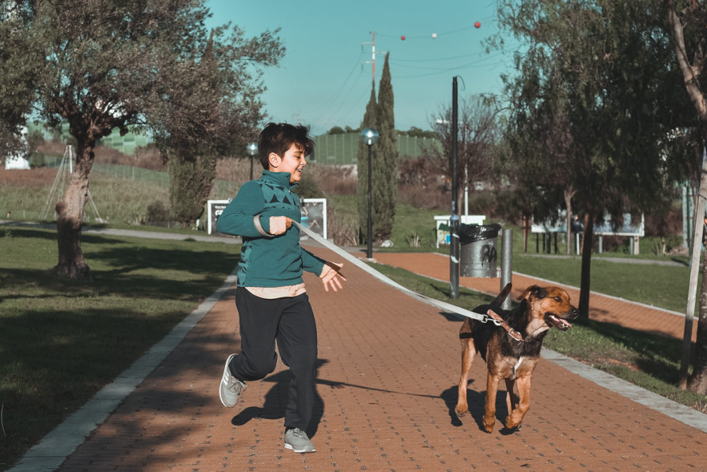 Criança a correr com cão pela trela
