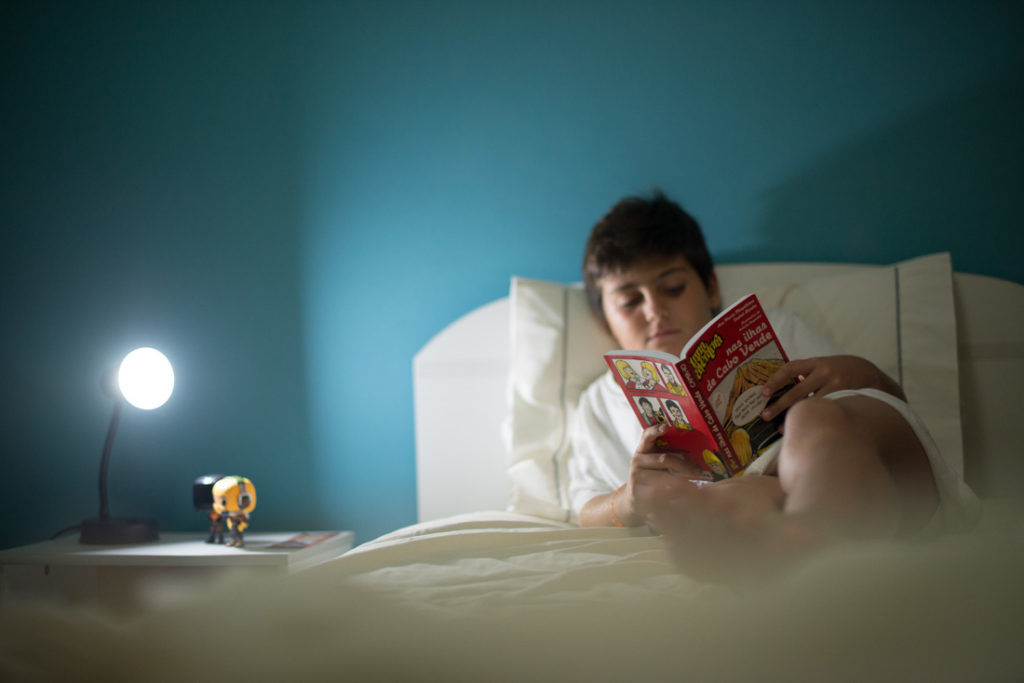Criança deitada no quarto a ler um livro